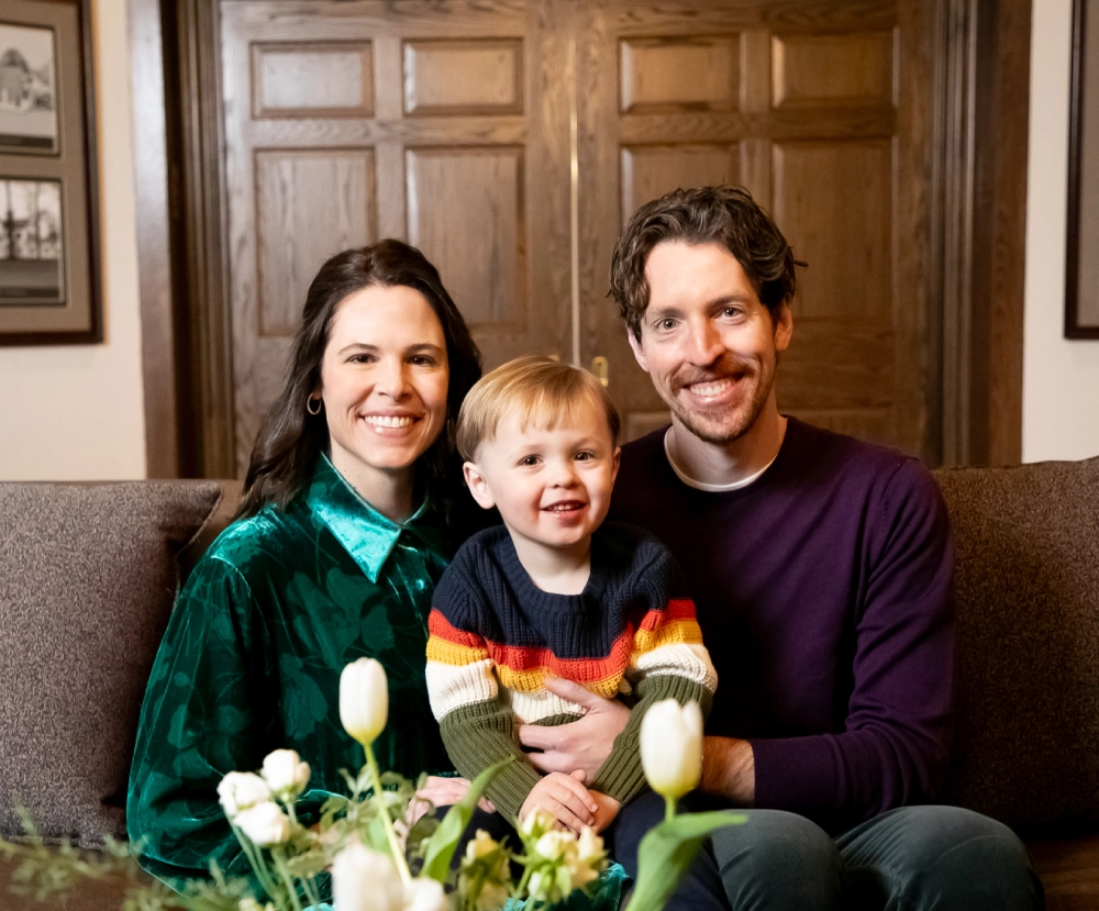 A man and woman holding a child on the couch